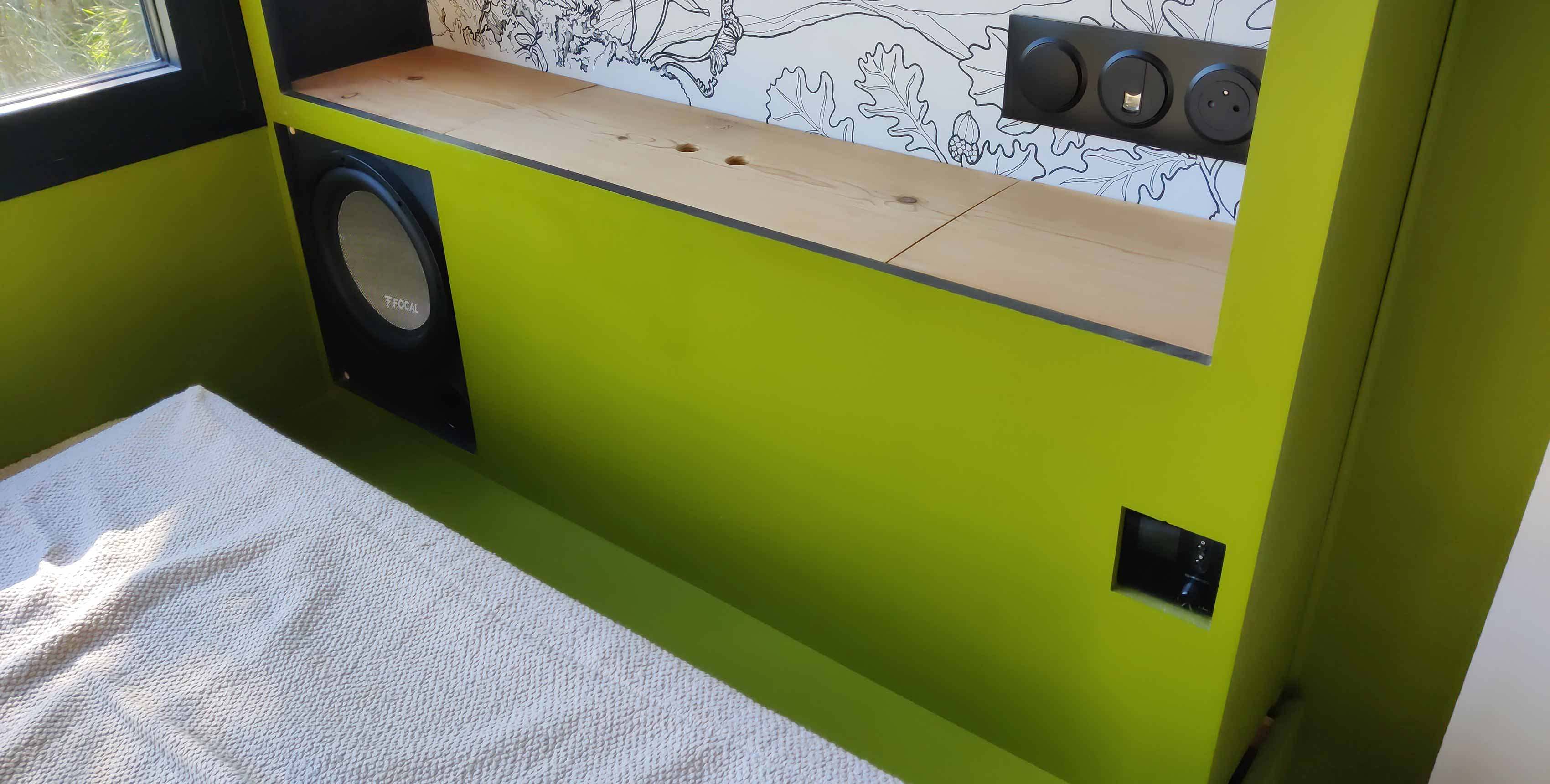 Meuble vert Tiny House avec un caisson de basse et un amplificateur audio.